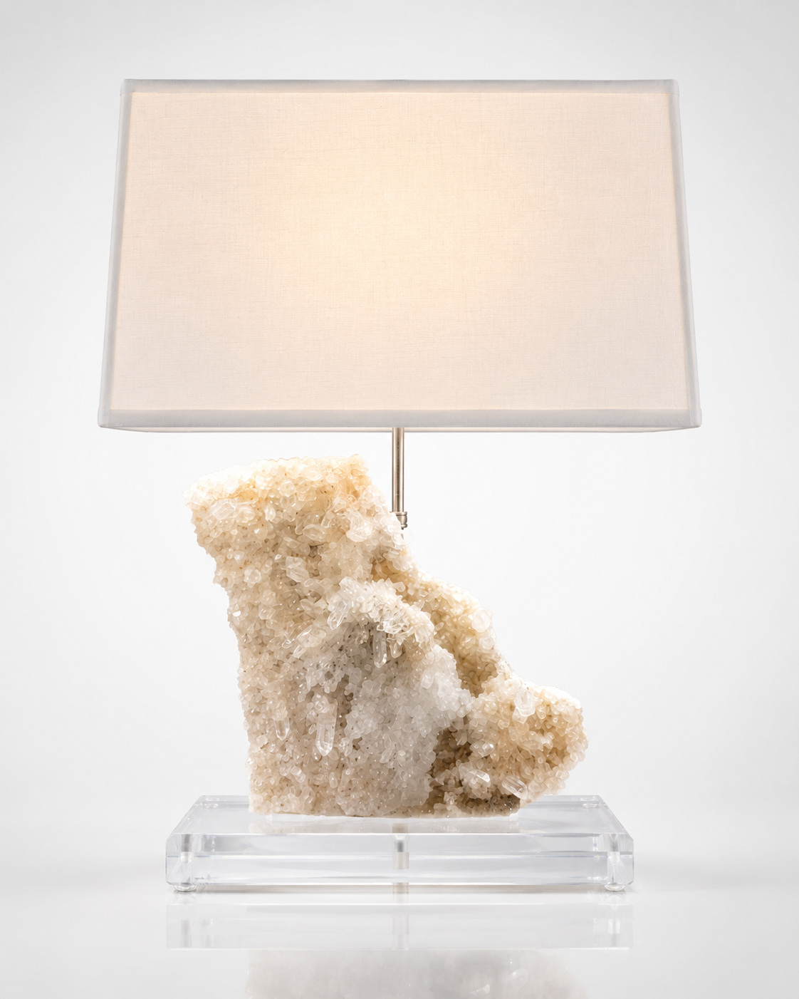 Quartz crystal geode table lamp with linen shade on a clear acrylic base