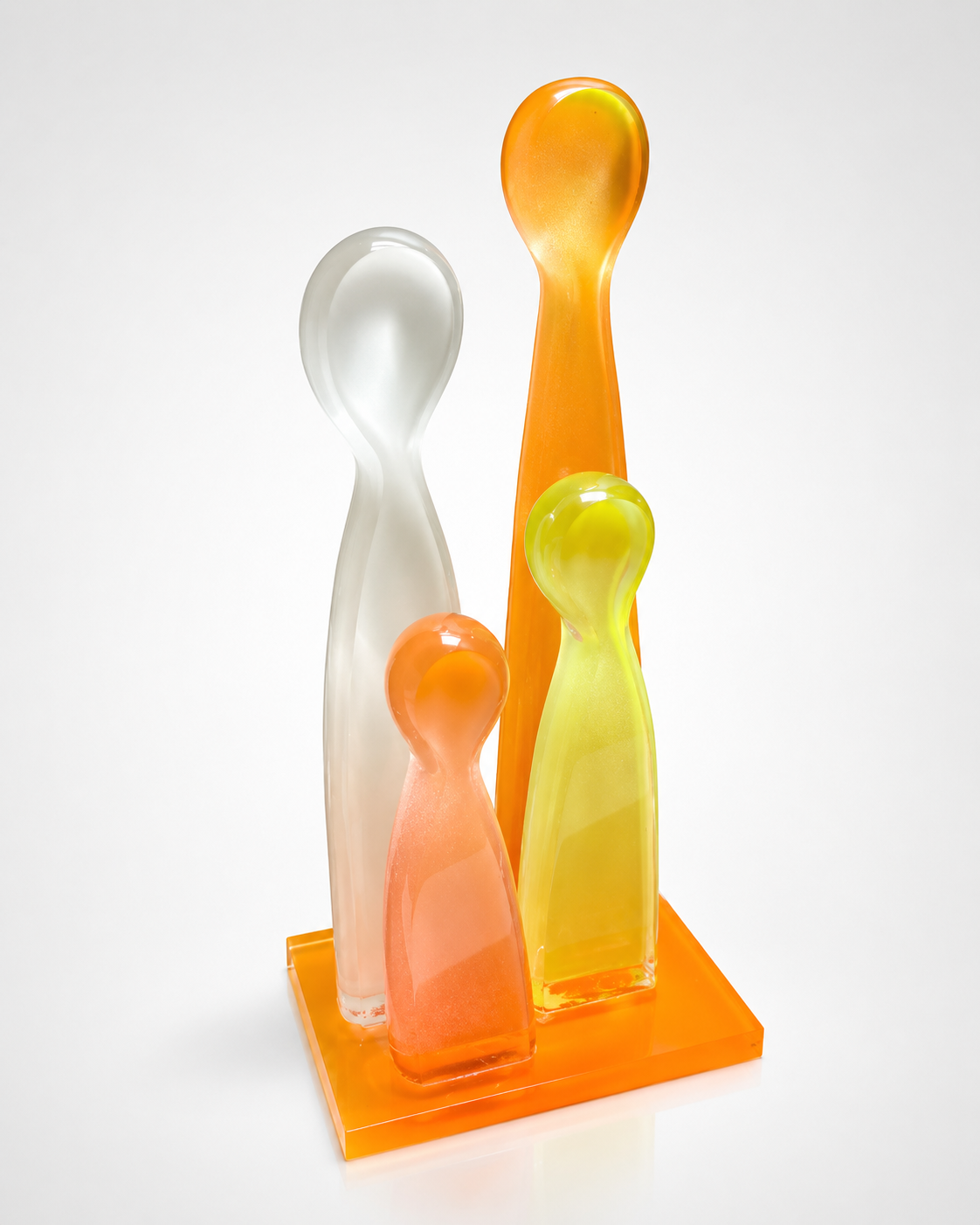 Four cast acrylic figurine sculptures in frosted, orange, and yellow tones on an orange acrylic base